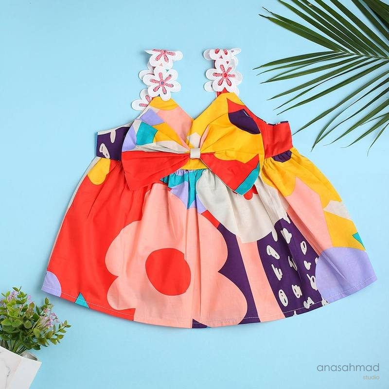 Colorful children's sundress with floral print and bow, on blue background