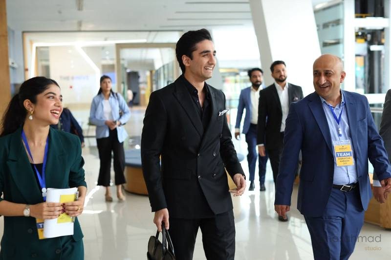 Group of business professionals walking and smiling in a modern office lobby at a DisruptHR Karachi event
