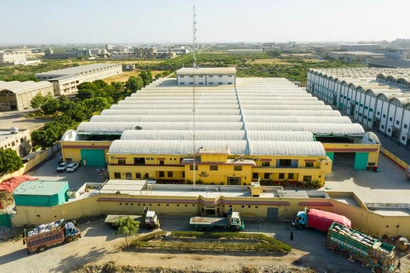Aerial view of a rice mill warehouse complex with delivery trucks and loading area