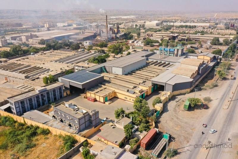 Aerial view of an industrial manufacturing facility with solar panels and smoke stack