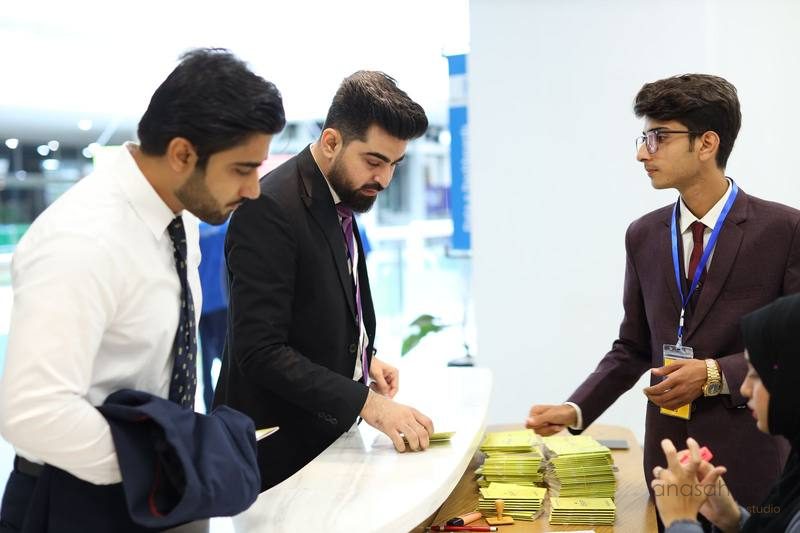 Event staff organizing registration materials at a reception desk