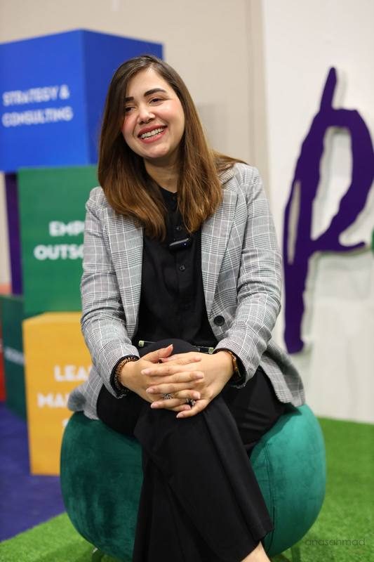 Businesswoman smiling, seated at a corporate expo booth