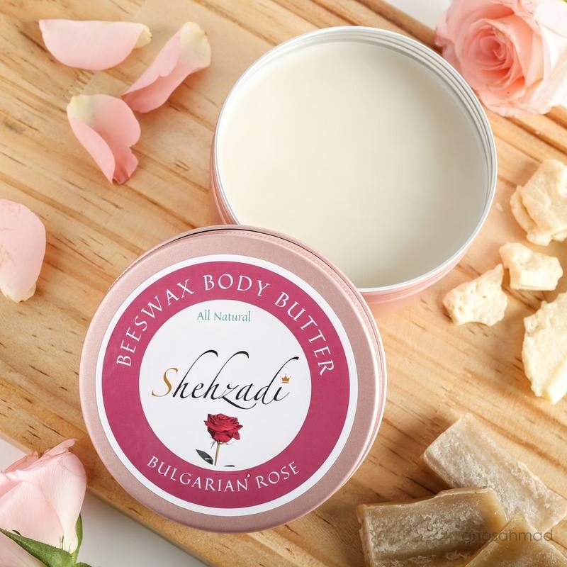 Shehzadi Beeswax Body Butter in Bulgarian Rose, open tin styled with rose petals on wood