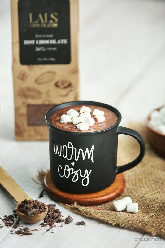 Hot chocolate with marshmallows in a Warm and Cozy mug beside a chocolate box