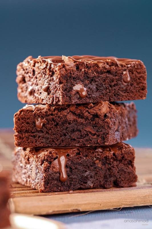 Stack of three fudgy chocolate brownies with chocolate drizzle