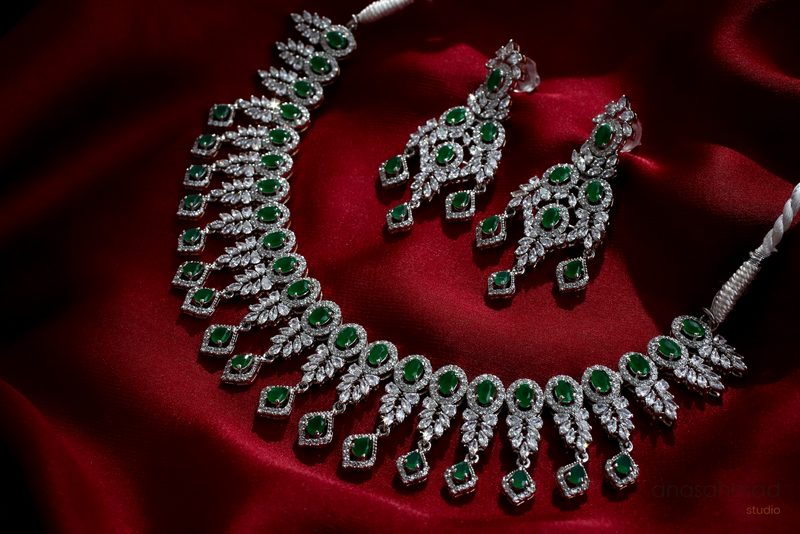 Emerald and diamond necklace and earring set on deep red silk