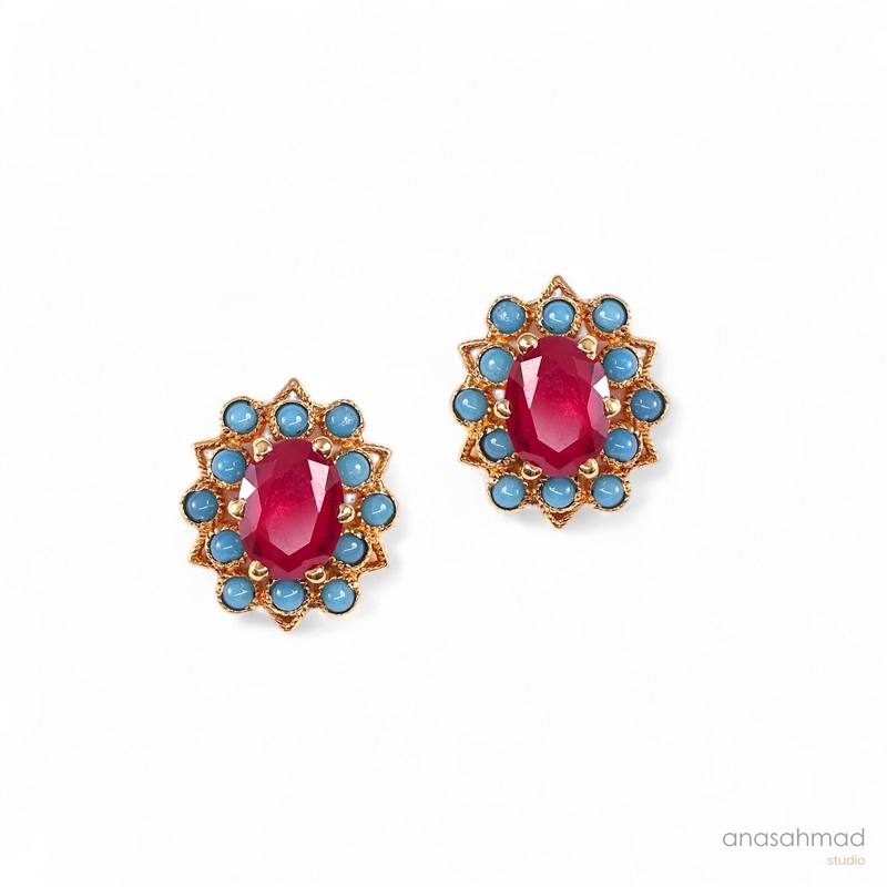 Ruby and turquoise gold stud earrings on white background