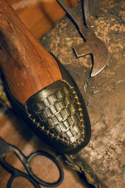 Woven leather shoe toe detail on a wooden shoe last, styled with cobbler tools