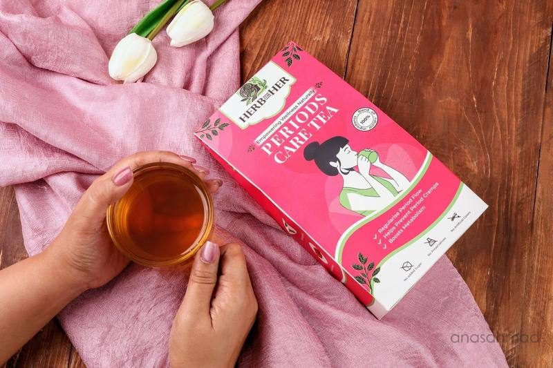 Herb for Her Periods Care Tea box styled with hands holding tea and tulips