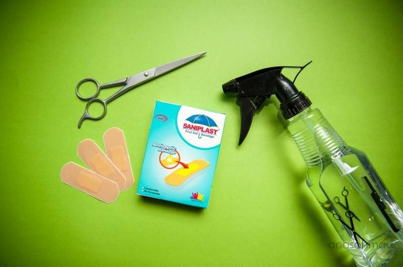 Saniplast antiseptic bandage box styled with scissors and spray bottle on green background