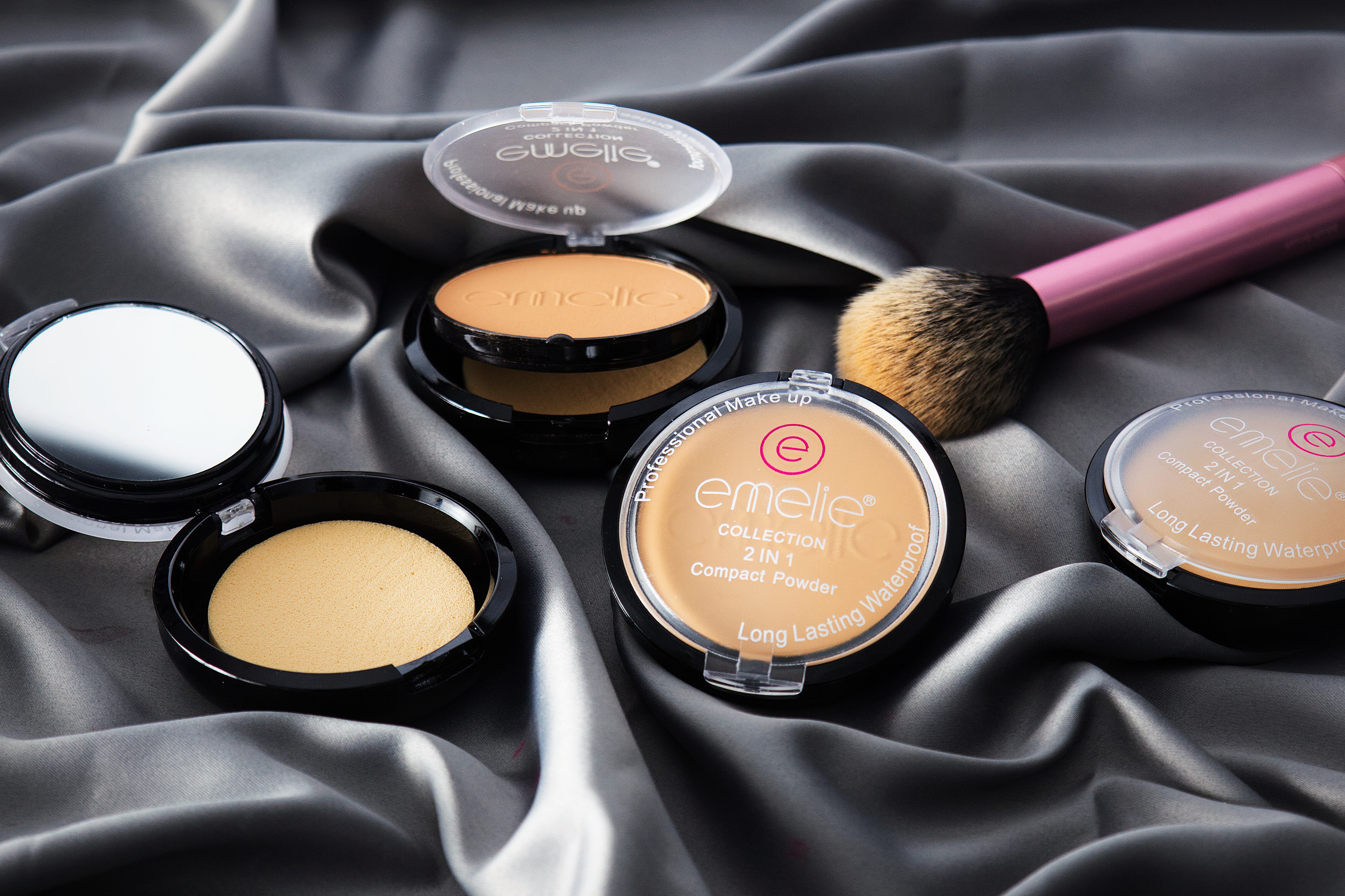 Professional makeup compact powder products with brush on satin fabric background