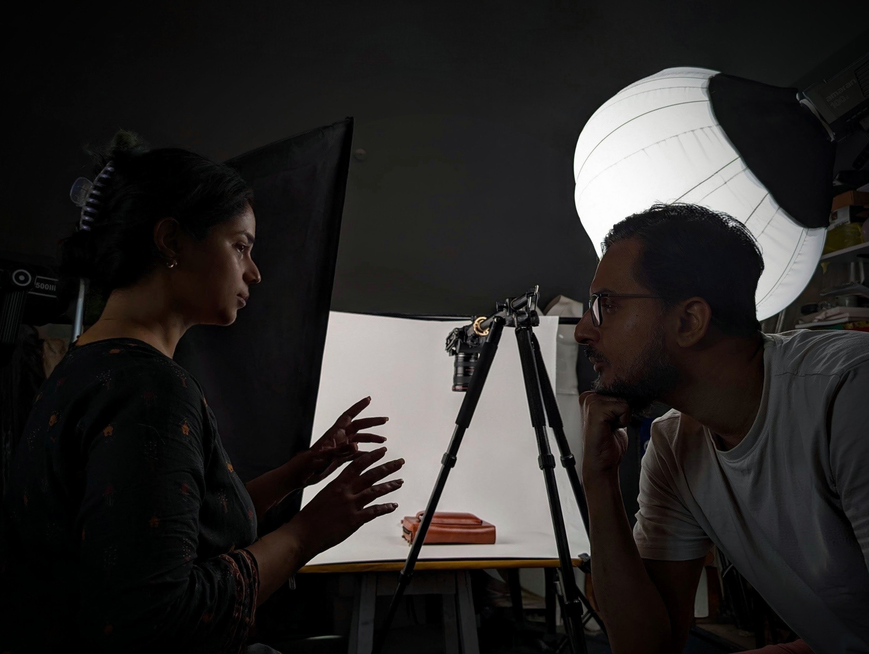 Professional product photography setup with photographer and assistant discussing lighting and composition in studio